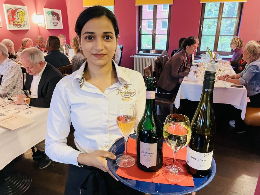 <who>Photo credit: Steve MacNaull/NowMedia Group</who>Roshni shows off the wines served at the farewell dinner at Heck-Art restaurant in Chemnitz -- Geldermann Grand Rose Sekt sparkling, left, and Borell Diehl Riesling Trocken.